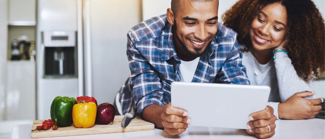 Man and woman smiling and looking at a laptop