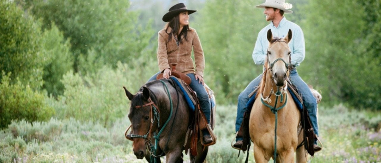couple riding on a trail ride riding horses