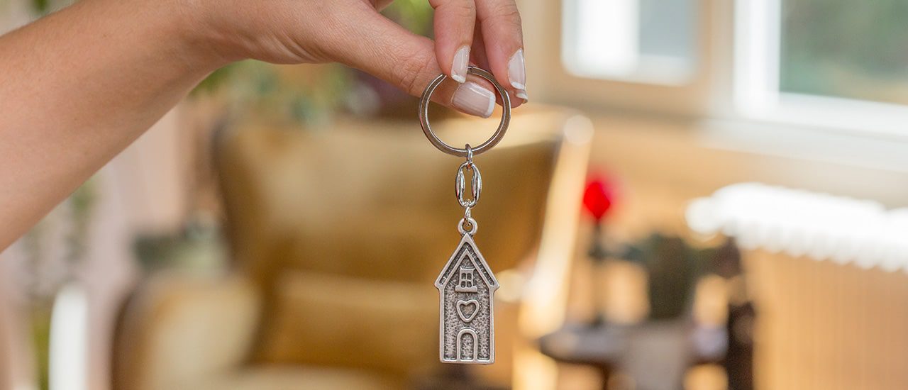 hand holding keychain with little house pendant