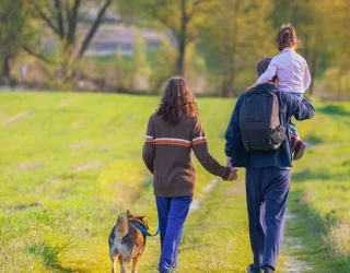 Family walking on a grassy trail with a dog in a peaceful outdoor setting near Dallas.