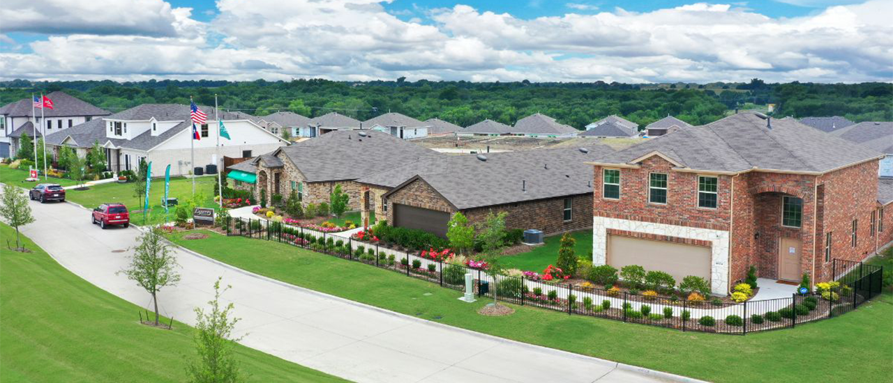 Aerial view of brick homes along landscaped suburban street.