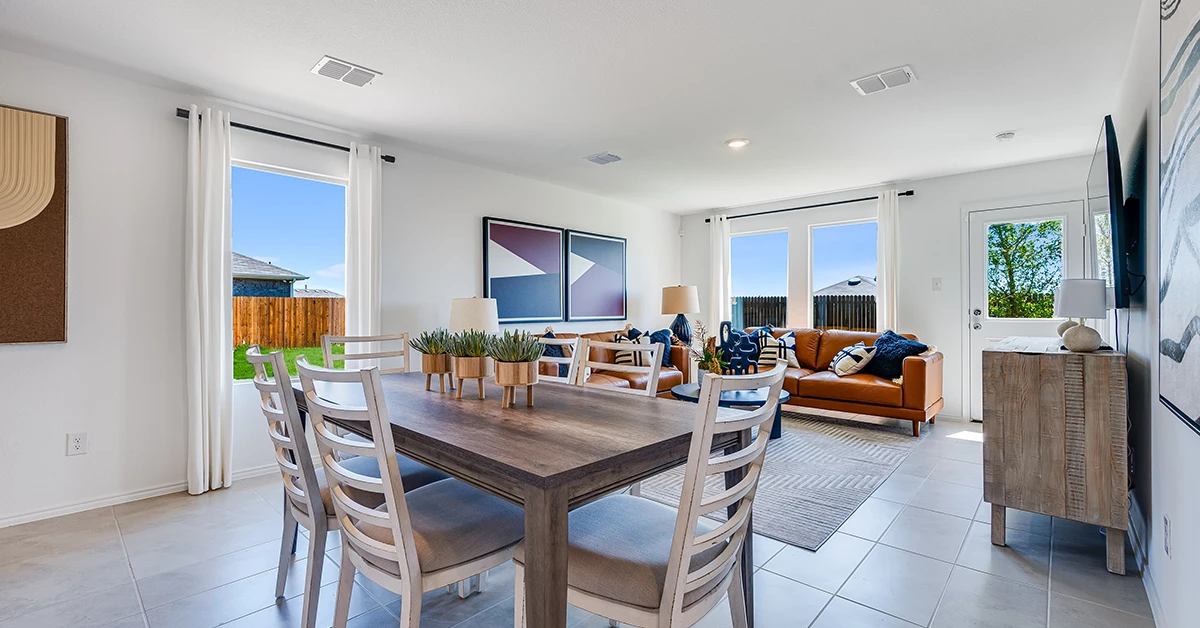 Open dining and living room with table, chairs, sofa, and large windows.