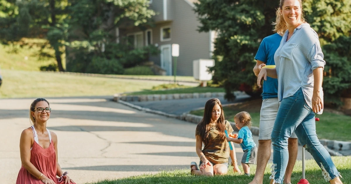 People socializing outdoors with children in neighborhood.